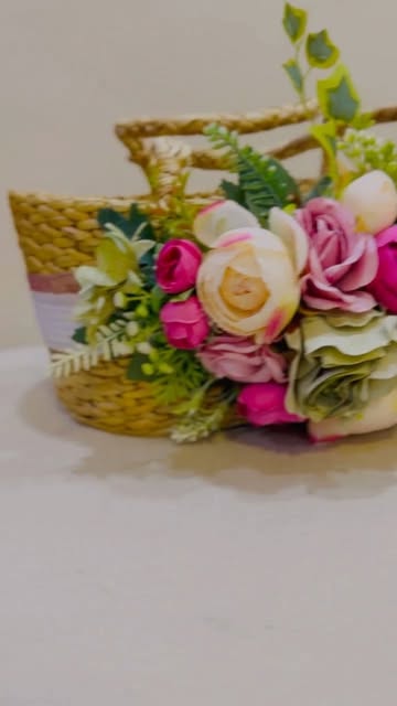 A woven basket decorated with pink and ivory roses and green foliage